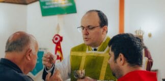 Ksiądz udzielający komunii świętej mężczyznom w kościele