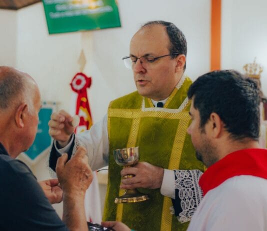 Ksiądz udzielający komunii świętej mężczyznom w kościele