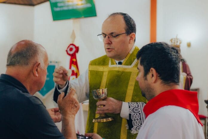 Ksiądz udzielający komunii świętej mężczyznom w kościele Ksiądz udzielający komunii świętej mężczyznom w kościele