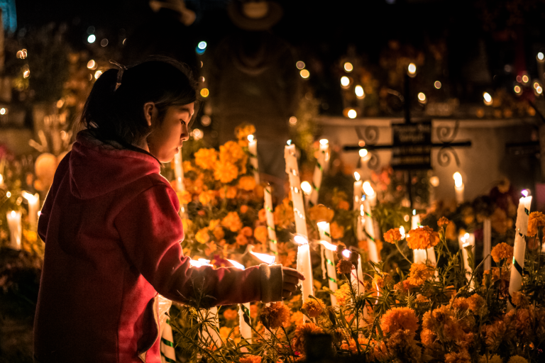 Dziewczynka zapala świece na cmentarzu w Oaxaca podczas Día de los Muertos